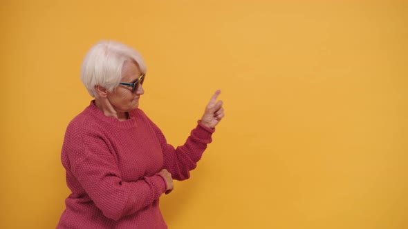Gray Haired Senior Woman with Sunglasses Pointing Fingers on Empty Space alt