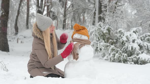 A young girl is building a snowman in a snowy park