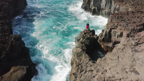 Aerial View of the Man Climbing Onto a Steep Rock alt