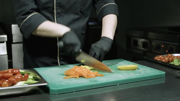 Cook's Hands in Black Gloves Slicing Yellow Paprika alt