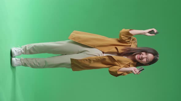 Full Body Of Asian Woman Using Phone With Credit Card And Celebrating In The Green Screen Studio alt
