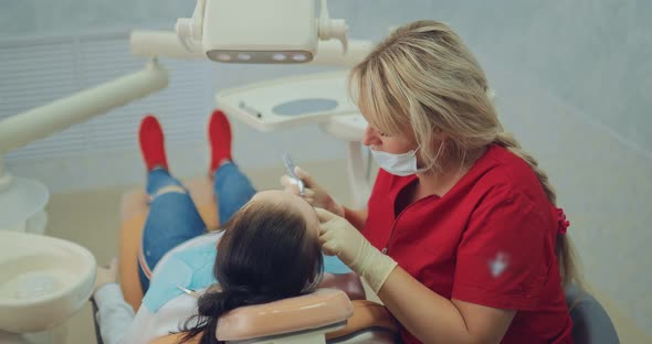 Pretty Woman Dentist Treats a Tooth to a Young Girl Works with the Tool alt