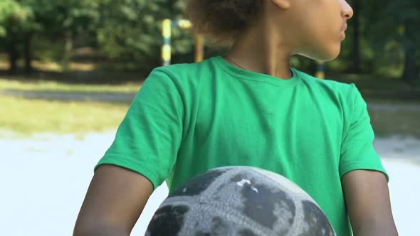 Sad Afro-American Teenager With Ball Looking Around, Lack of Sport Players