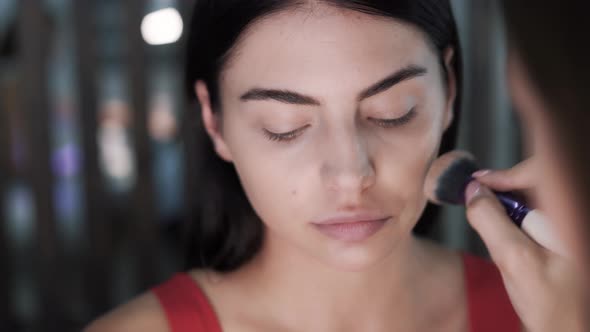 Makeup Artists Hand Applies Foundation to Charming Caucasian Brunette alt