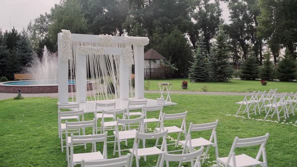 Beautiful wedding arch in the park with white chairs