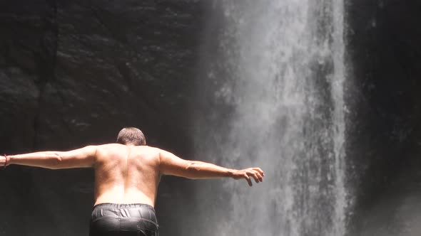 Fearless Young Man Diving Into the Stream on the Foot of a Powerful Waterfall