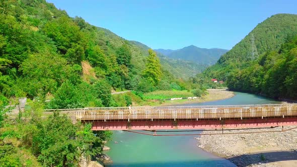 Aerial side view of a man crossing a bridge in Georgia over the Chorokhi River, alt