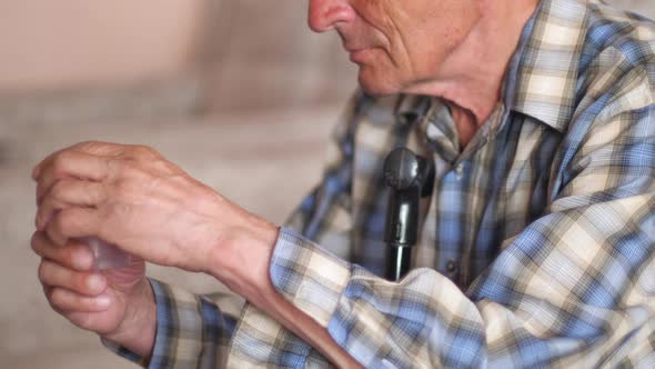 Elderly Caucasian man 70-79 years old sitting holding a container for tests. Senior citizen taking m alt