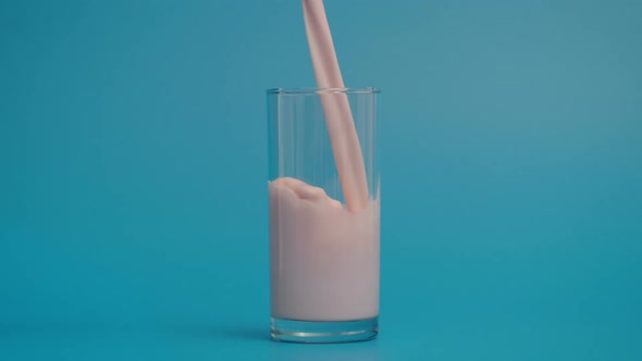 Super Slow Motion of Pouring Milk in Glass Blue Background alt