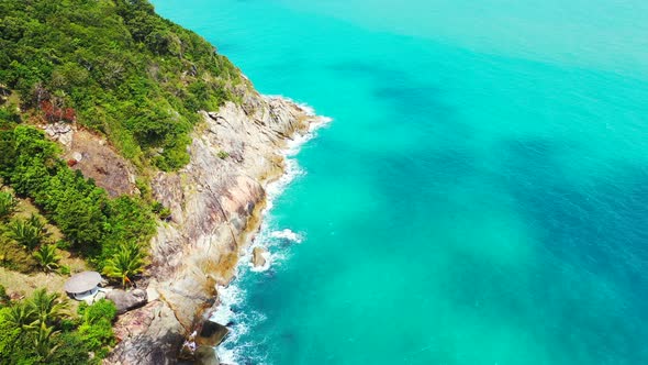Beautiful shoreline of tropical island with lush vegetation, rocky coast splashed by waves of turquo alt