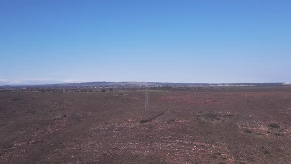 Drone Flying Towards Electric Pylon in Open Field