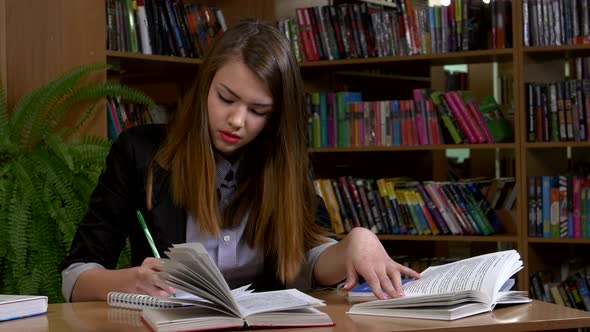 Portrait of Clever Student with Open Book Reading It in College Library alt