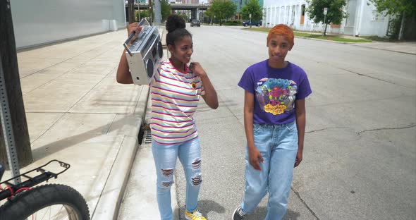 Two young attractive females dancing to music on boombox alt