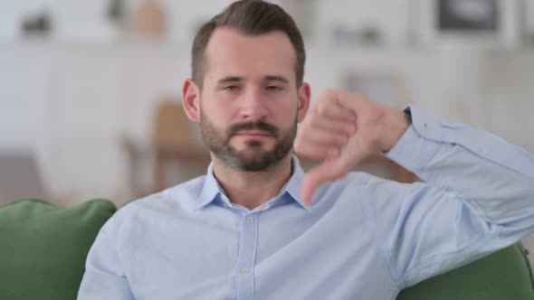 Young Man with Thumbs Down at Home alt