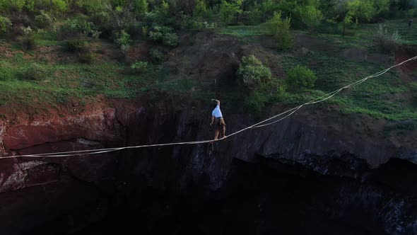 Aerial Footage of a Man Walking on a Tightrope Dark Abyss Is Under Him alt