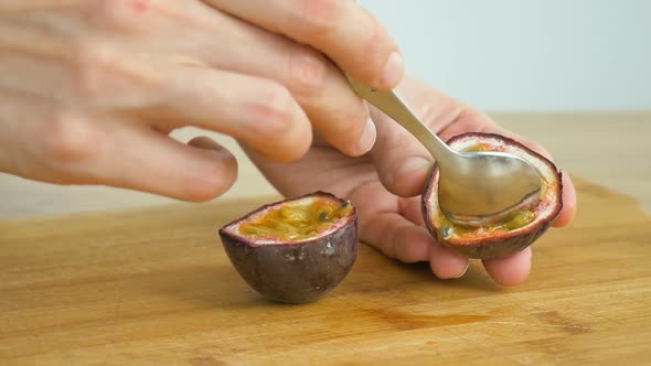 Female Eats Fresh Organic Ripe Granadilla or Yellow Passion Fruit with a Spoon alt