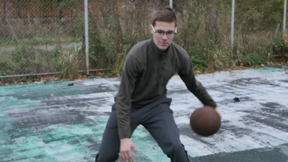 Caucasian Young Man with Glasses Training One Basketball Outdoors