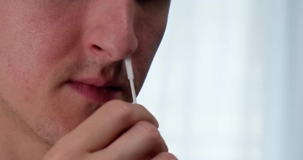 Man using nasal swab to take rapid self test for Covid-19. alt