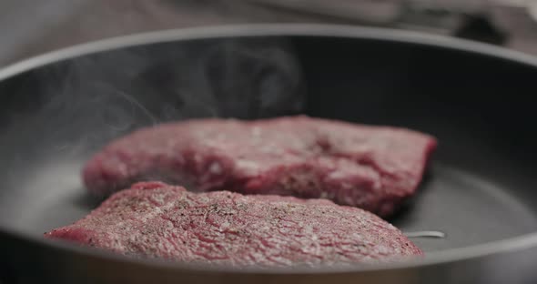 Slow Motion Two Beef Steak Pieces Frying on Nonstick Pan alt