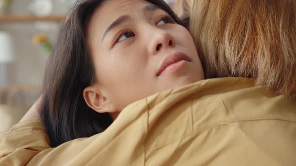 Sad young asian woman hug cuddle embracing with best friend in living room at home support.