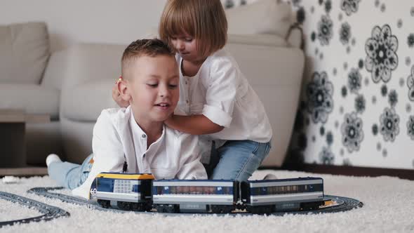 Portrait of Brother and Sister Playing with Toy Railroad at Home alt