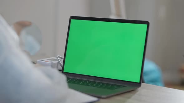 Closeup of Chromakey Laptop with Unrecognizable Doctor Sitting at Table Talking alt