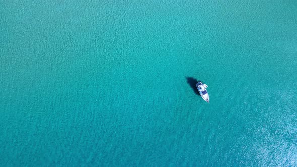 Sandy seafloor with some coral in the foreground and waves in the background alt