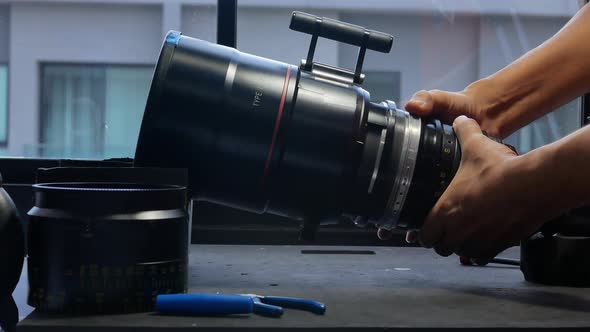 Human hands are rotating the focusing system of the big movie camera zoom lens.