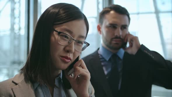 Businesspeople talking on mobile phones alt