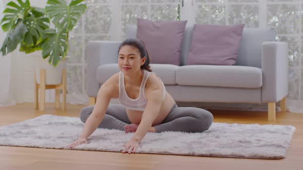 Happy Attractive Asian Pregnant woman practice yoga baddha konasana pose alt