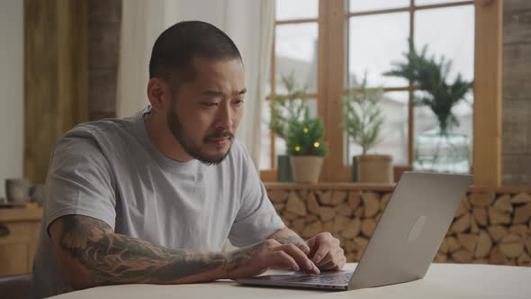 A Bunch of Various Facial Expressions By a Tattoed Asian Man in Front of His Laptop alt