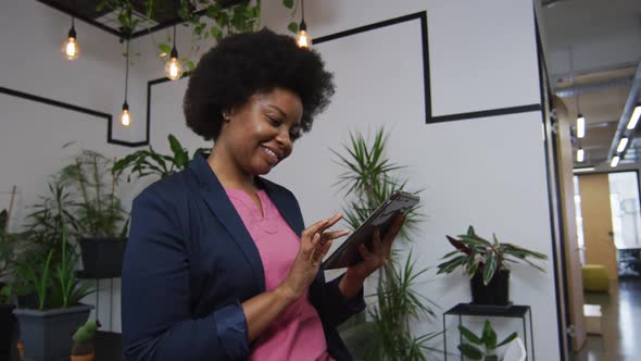 Portrait of african american woman smiling while using digital tablet at office alt