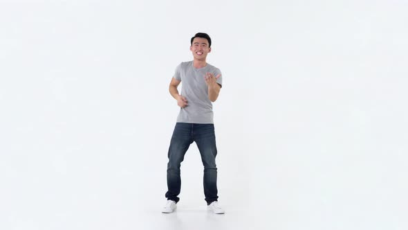 Asian man in gray t-shirt and blue jeans dancing and moving to music