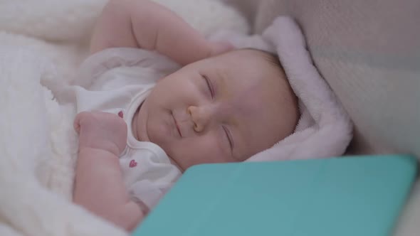 Charming Carefree Innocent Baby Girl Waking Up in Bed with Tablet Lying Aside alt