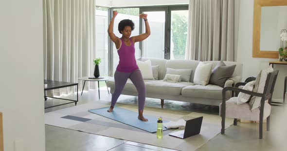 Happy african american wearing sportswear, exercising, using laptop alt