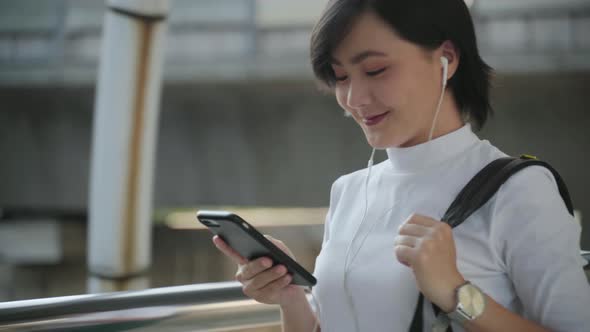 Portrait of asian woman with earphone listening music and using smartphone