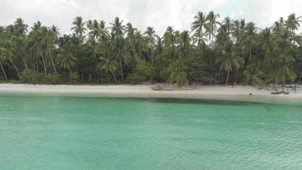 Aerial: woman relaxing on white sand beach turquoise water tropical alt