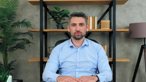 Businessman in home office looks camera listens conducts online interview potential employee company alt