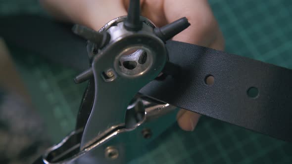 Skilled Worker Makes Holes in Leather Belt Close View alt