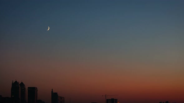 Half Moon Above City Buildings alt