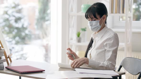Young Slim Woman in Face Mask Disinfecting Workplace on Coronavirus Pandemic alt