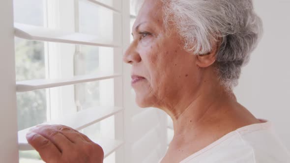 Senior African American woman looking at her window, at home alt