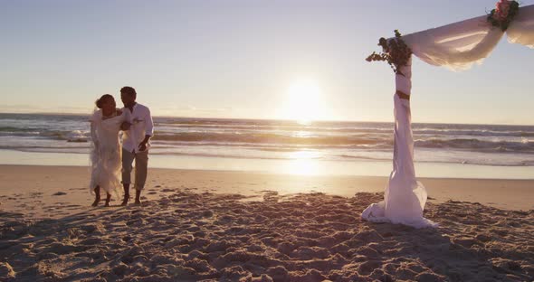 African american couple in love getting married, walking on the beach at sunset alt