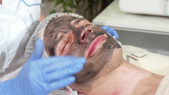 Cosmetologist Preparing Face of Male Client for Carbon Facial Peeling alt
