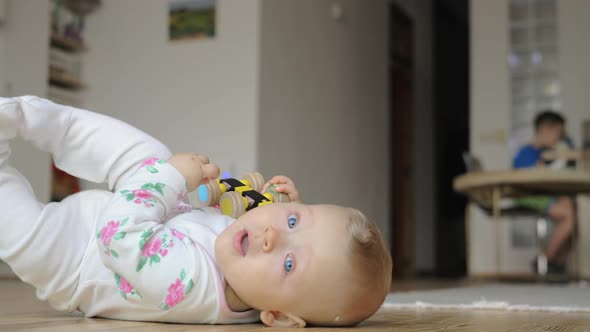 A Baby Girl in a Romper Suit Lying on the Floor alt