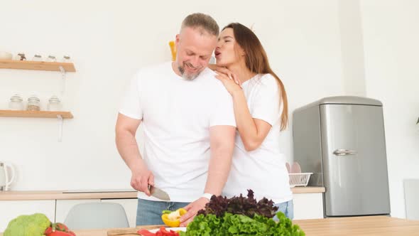 The Husband Prepares Vegetarian Food for His Wife She Hugs Him Tenderly alt