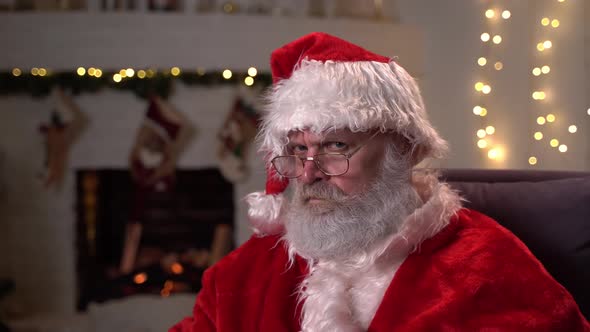 Portrait of the Fearsome Santa Claus in Glasses, Sitting in His Rocking Chair and Menacingly Shows