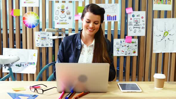 Female executive using laptop and digital tablet at desk alt