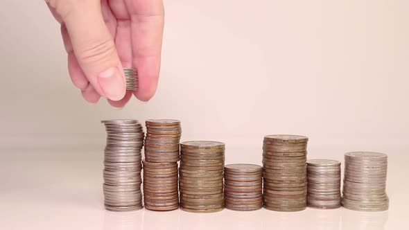 A woman's hand puts coins in a column. Investment concept. Metallic currency. alt