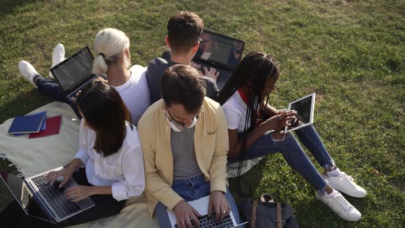 Diverse Mates Using Gadgets While Studying Outdoor alt